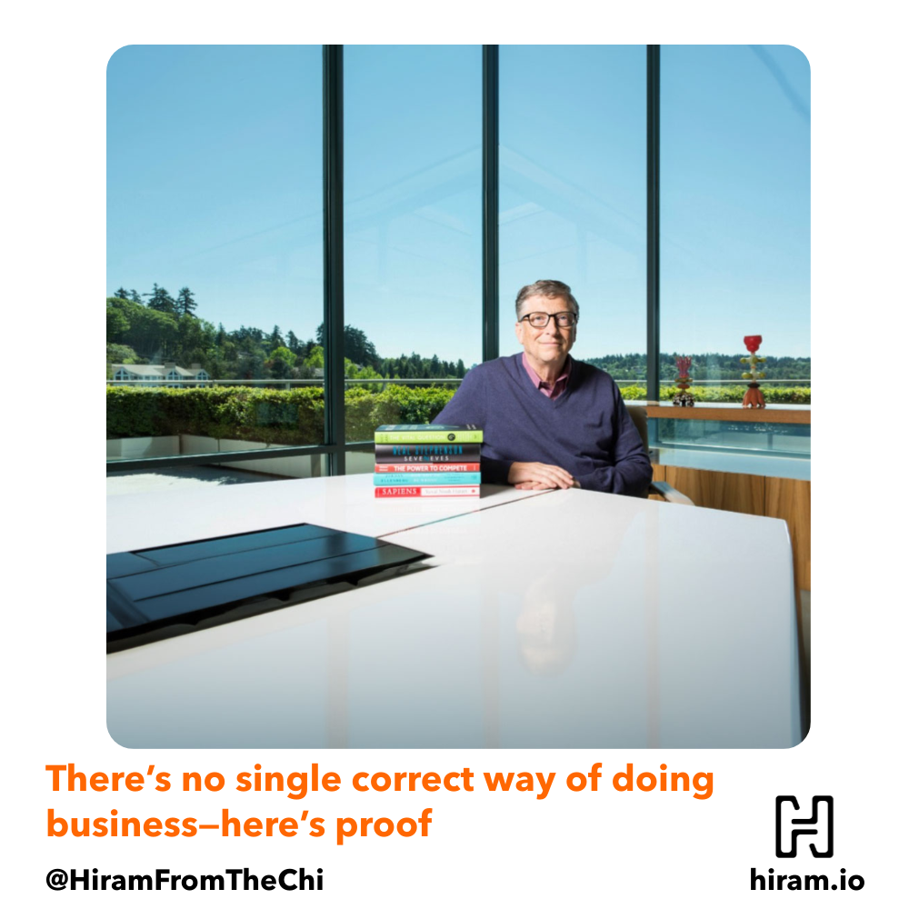Bill Gates sitting in front of a big table with his books.